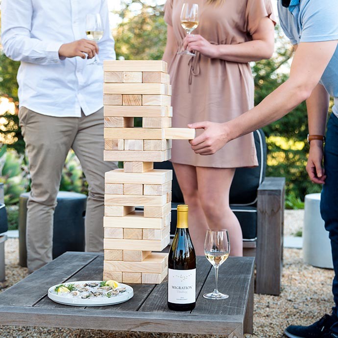 Three people playing janga and drinking Migration Chardonnay