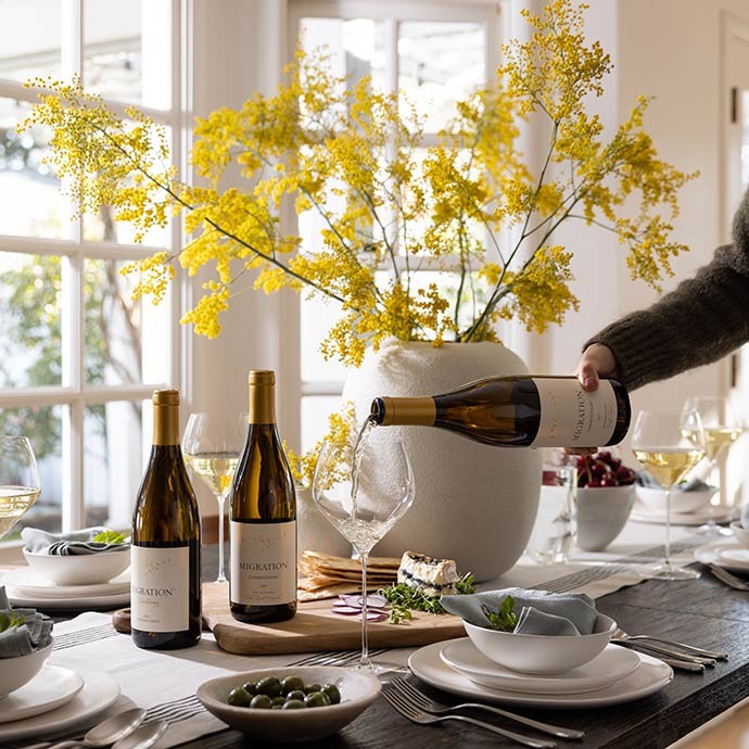 Three Migration wines on a table and a chardonnay is being poured
